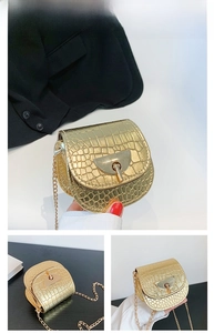 Detail of gold faux leather saddle bag with crocodile texture and metal chain strap