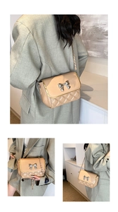 Detail of beige quilted crossbody bag with silver bow buckle and gold trim