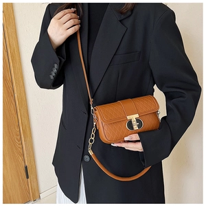 Detailansicht der braunen gesteppten Umhängetasche mit goldenem T-Verschluss und Blazer