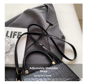 Detail of black crocodile texture handbag with woven handle and adjustable strap