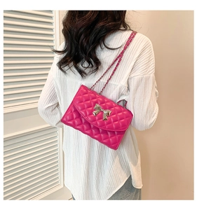 Detail of rose pink quilted mini bag with silver bow buckle and chain strap on shoulder