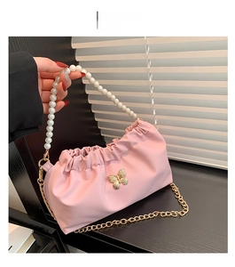 Dettaglio della borsa a nuvola rosa con fiocco dorato e manico di perle elegante