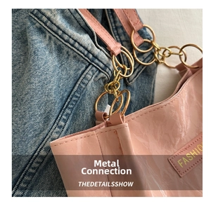 Dettaglio della borsa rosa lucida con anello in metallo e patch con scritta FASHIO