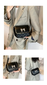 Detail view of black quilted crossbody bag with gold bow clasp and metal chain strap
