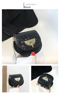 Close-up of black crocodile texture saddle bag with golden chain and metal buckle