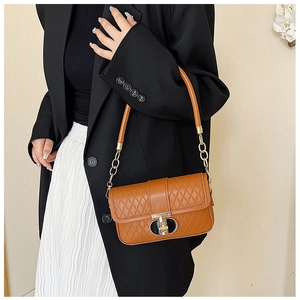 Braune Stepptasche mit goldener Kette am schwarzen Blazer von Model präsentiert