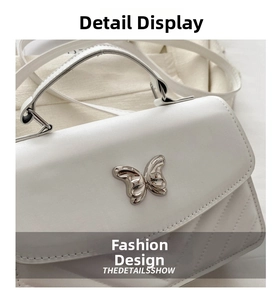 Detail of white leather handbag featuring V-quilted pattern and silver butterfly metal buckle