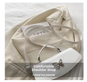 Detailed close-up of white leather handbag featuring a butterfly metal buckle on fabric