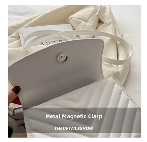Close-up of the high-quality hardware magnetic snap closure on a white quilted handbag
