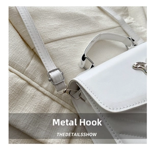 Detailed close-up of the silver metal hook and quilted leather strap on a white bag