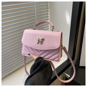 Detail of pink small square bag featuring V-shaped quilting and silver butterfly accent