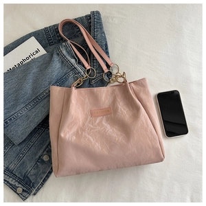 Dettaglio della borsa tote rosa con texture stropicciata, catena d'oro e logo tag