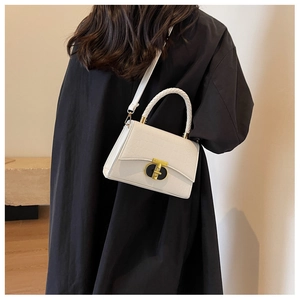 Detail of white crocodile pattern handbag featuring a woven handle and golden metal clasp