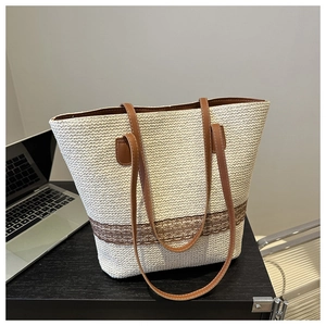 Detail of hand-woven straw tote bag with brown leather handles and decorative lace trim