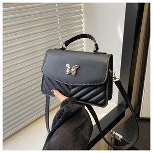 Detail of black crossbody bag with silver butterfly emblem and V-shaped quilting