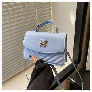 Detail of light blue square crossbody bag with silver butterfly clasp and V-quilted texture