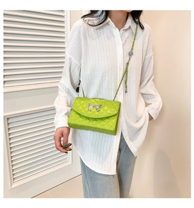 Détail du sac à bandoulière matelassé vert avec nœud argenté et chaîne métal