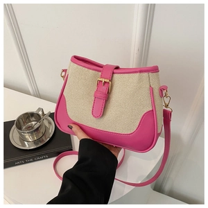 Detail of canvas bag featuring pink leather trim and a decorative gold metal buckle