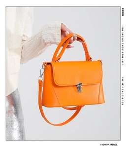 Detail view of orange PU leather baguette bag with silver buckle and detachable strap