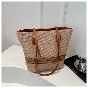 Detail of woven straw tote bag with brown leather straps and striped texture design