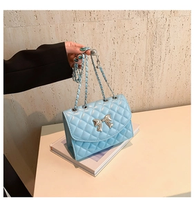 Détail du sac à bandoulière matelassé bleu clair avec nœud métallique argenté et chaîne