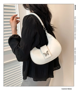 Détail du sac à bandoulière blanc en demi-lune avec ornement papillon en métal argenté