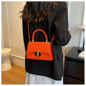 Detail of orange faux-crocodile leather bag with woven handle and gold hardware locks