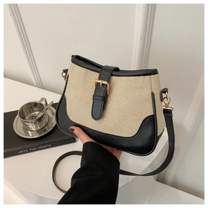 Detail of woven beige canvas and black leather crossbody bag with golden metal buckle