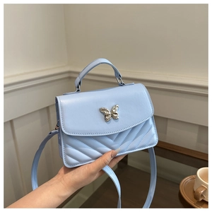 Detail of light blue crossbody bag with silver butterfly buckle and V-quilted texture