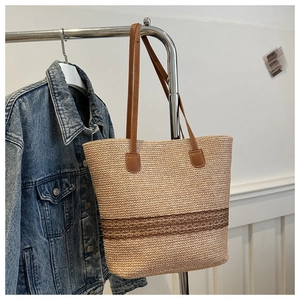 Detail of hand-woven straw tote bag with brown lace stripes and leather handles