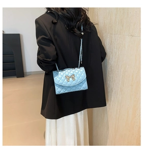 Gros plan d'un sac à bandoulière matelassé bleu clair avec boucle nœud doré et chaîne
