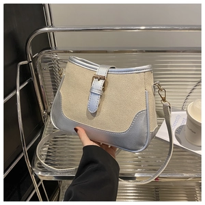 Detail of beige canvas and silver leather crossbody bag with metallic buckle