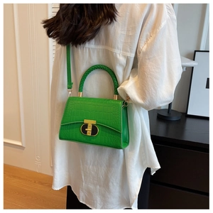 Detail of green faux crocodile skin texture and gold T-shaped clasp on a handbag