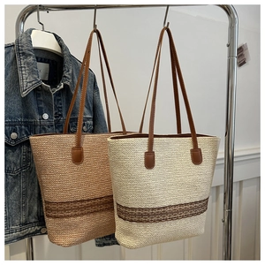 Detail of woven straw tote bag with crochet lace trim and brown leather handles