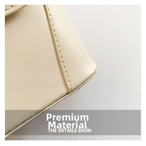 Detailed close-up of cream leather texture and precise stitching on a small square handbag