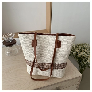 Detailed close-up of woven straw tote bag with lace trim and brown leather handles