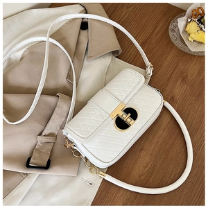 Detail einer weißen Stepptasche mit runder Goldschließe und eleganter Kettenschultergurt