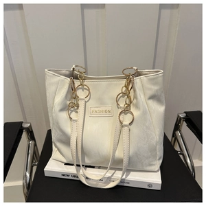 Dettaglio della borsa tote crema effetto marmo con logo metallico dorato e catenella
