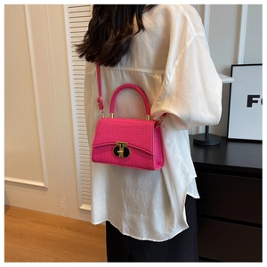 Magenta crocodile pattern handbag with woven handle and gold clasp on a model