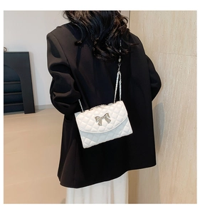 Sac bandoulière blanc matelassé avec nœud en métal porté par un mannequin femme