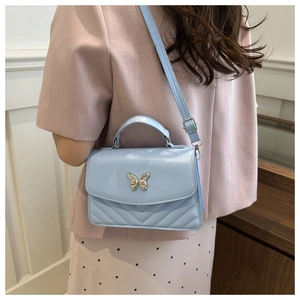 Detailed view of baby blue crossbody bag with silver butterfly and V-quilted pattern