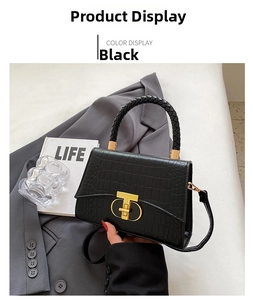 Close-up of black crocodile embossed handbag featuring a golden T-shaped metal clasp