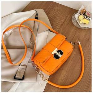 Detail einer leuchtend orangefarbenen Stepptasche mit goldenem Drehverschluss und Kette