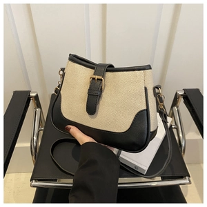 Detail of canvas crossbody bag showing contrast stitching and gold metal buckle hardware