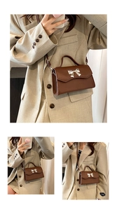 Close-up of brown leather handbag featuring a silver metal bow buckle and top handle