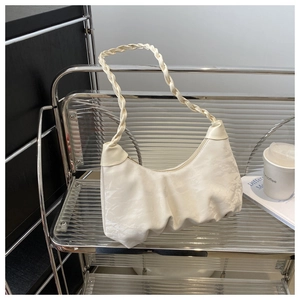 Détail du sac baguette blanc froncé montrant l'anse tressée et le cuir souple