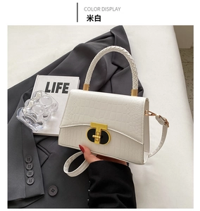 Detailed view of off-white handbag with crocodile pattern and stylish woven top handle
