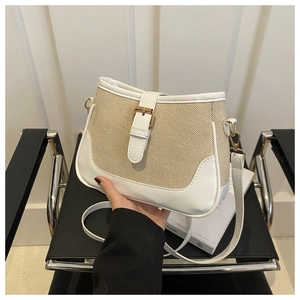 Detail of beige canvas and white leather crossbody bag with gold buckle on black chair