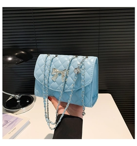 Detail of light blue quilted crossbody bag with silver bow hardware and chain strap