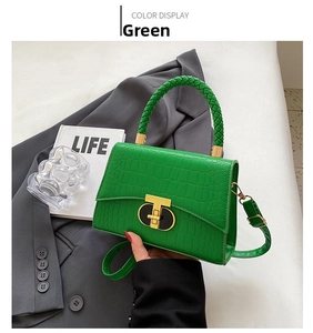 Detail of green crocodile pattern handbag with woven handle and gold T-lock closure